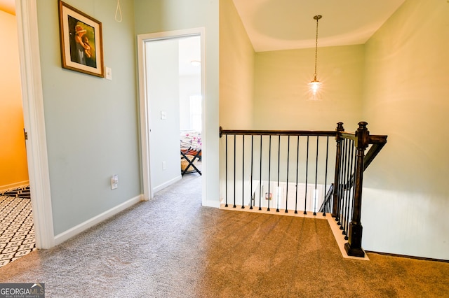 hallway with carpet floors, an upstairs landing, and baseboards