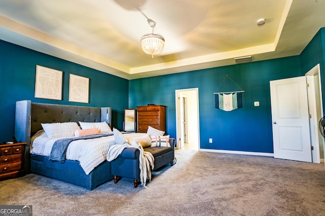 carpeted bedroom with a tray ceiling, baseboards, and a chandelier
