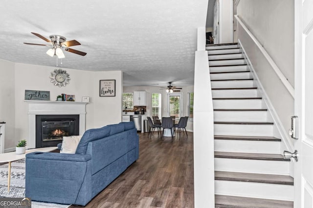 26 Springbottom Dr, Lawrenceville, GA 30046 - living room with ceiling fan, stairway, dark wood finished floors, a glass covered fireplace, and a textured ceiling