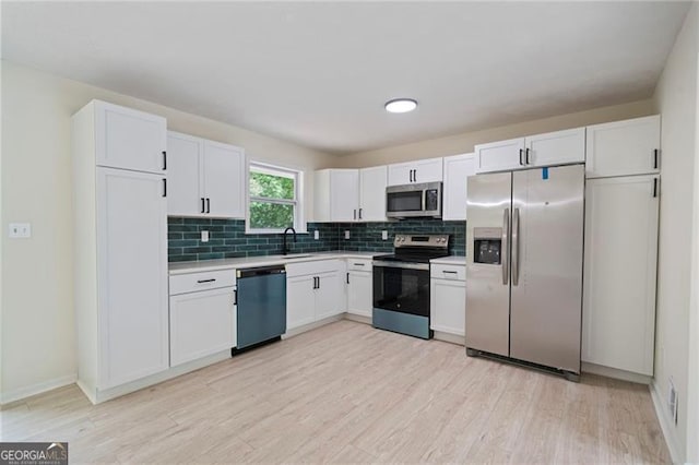 8432 Magnolia Dr, Jonesboro, GA 30238 - kitchen featuring appliances with stainless steel finishes, decorative backsplash, white cabinets, light countertops, and light wood-type flooring