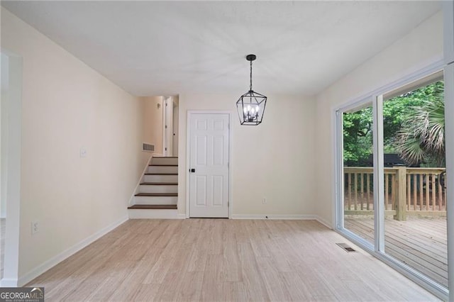 8432 Magnolia Dr, Jonesboro, GA 30238 - unfurnished dining area featuring light wood-type flooring, baseboards, stairway, and a chandelier