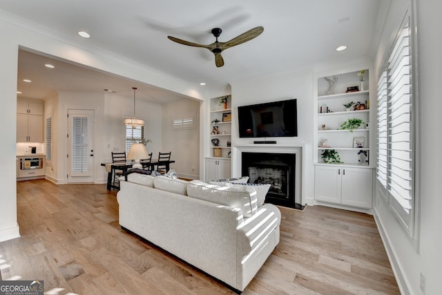 living area with a ceiling fan, a fireplace, light wood finished floors, baseboards, and recessed lighting