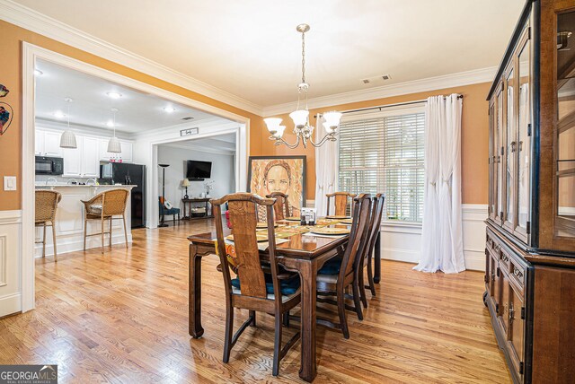 725 Windsor Place Cir SW, Grayson, GA 30017 - dining room with a chandelier, light wood-style floors, ornamental molding, wainscoting, and a decorative wall