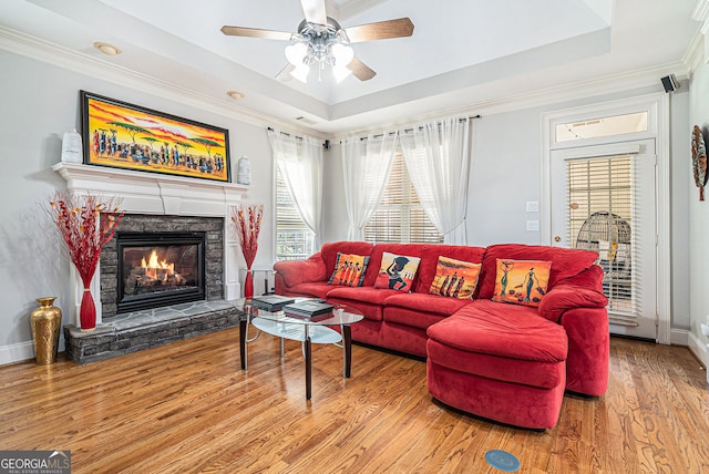 725 Windsor Place Cir SW, Grayson, GA 30017 - living room with a tray ceiling, a stone fireplace, wood finished floors, a ceiling fan, and crown molding