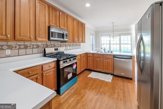 161 Pleasant Grove Rd, Mcdonough, GA 30252 - kitchen with stainless steel appliances, ornamental molding, a sink, light wood-style flooring, and tasteful backsplash