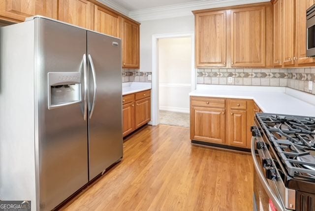 161 Pleasant Grove Rd, Mcdonough, GA 30252 - kitchen featuring appliances with stainless steel finishes, light countertops, light wood-style floors, backsplash, and crown molding