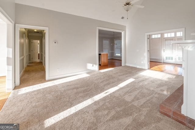 161 Pleasant Grove Rd, Mcdonough, GA 30252 - unfurnished living room with carpet floors, ceiling fan, baseboards, and a towering ceiling