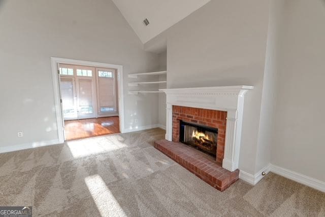 161 Pleasant Grove Rd, Mcdonough, GA 30252 - unfurnished living room with carpet floors, a brick fireplace, high vaulted ceiling, and baseboards