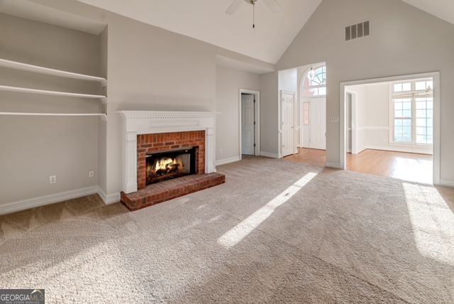 161 Pleasant Grove Rd, Mcdonough, GA 30252 - unfurnished living room featuring high vaulted ceiling, carpet floors, a ceiling fan, a fireplace, and baseboards