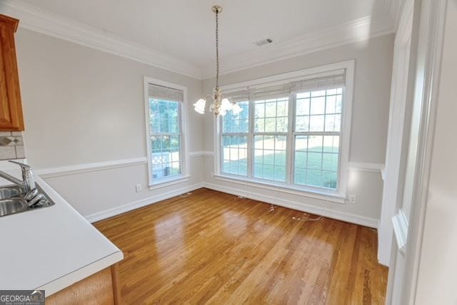 161 Pleasant Grove Rd, Mcdonough, GA 30252 - unfurnished dining area with crown molding, healthy amount of natural light, light wood-style flooring, and a chandelier