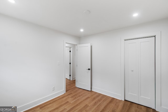 unfurnished bedroom featuring recessed lighting, light wood-style flooring, baseboards, and a closet