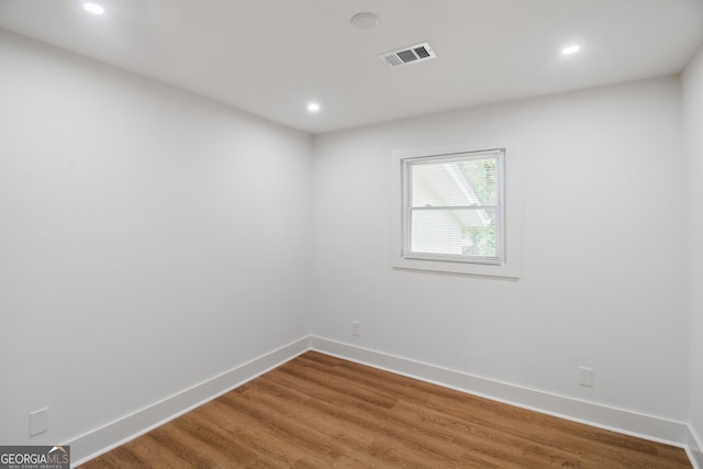 spare room with baseboards, wood finished floors, and recessed lighting