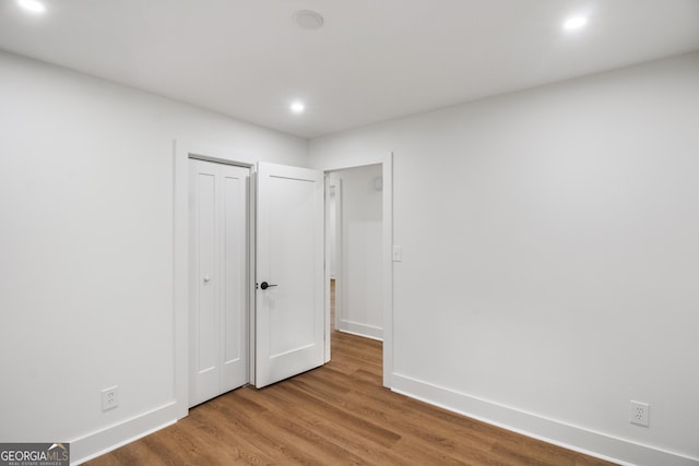 unfurnished bedroom with recessed lighting, baseboards, wood finished floors, and a closet