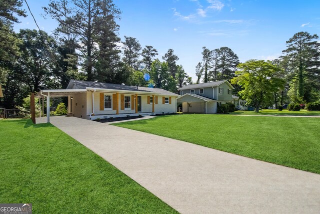 view of front of home with concrete driveway, an attached carport, a front lawn, and covered porch