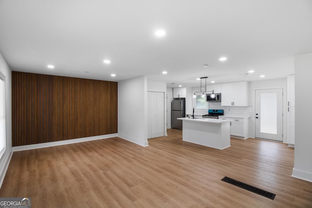 kitchen featuring appliances with stainless steel finishes, recessed lighting, a sink, a kitchen island, and open floor plan