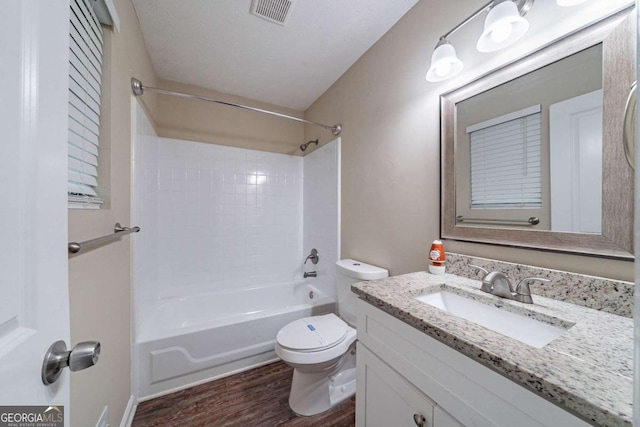 bathroom featuring toilet, wood finished floors, vanity, and bathing tub / shower combination
