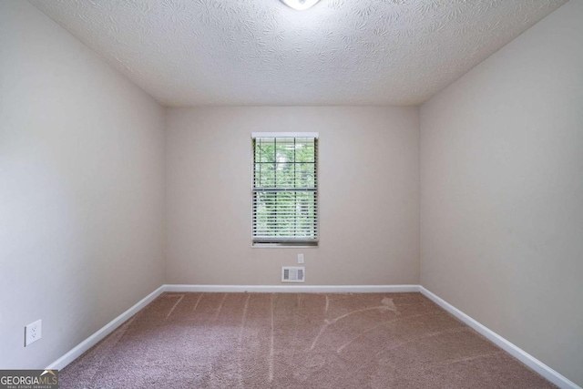 carpeted spare room featuring baseboards and a textured ceiling