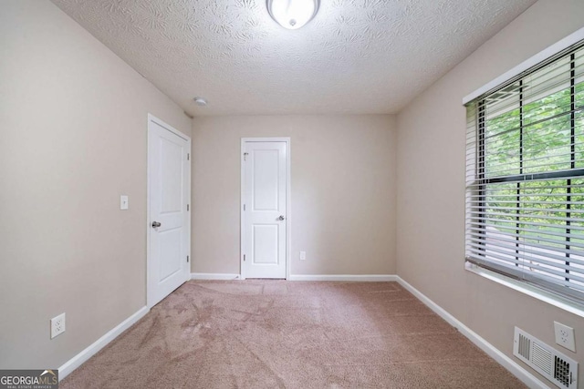 carpeted empty room with a textured ceiling and baseboards