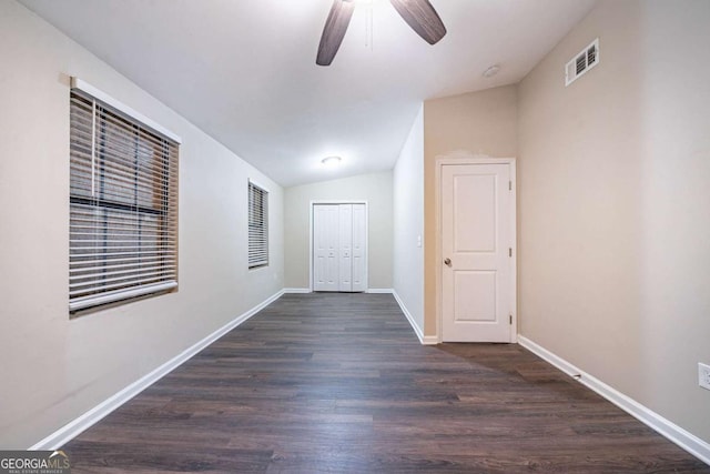 empty room with vaulted ceiling, a ceiling fan, dark wood finished floors, and baseboards