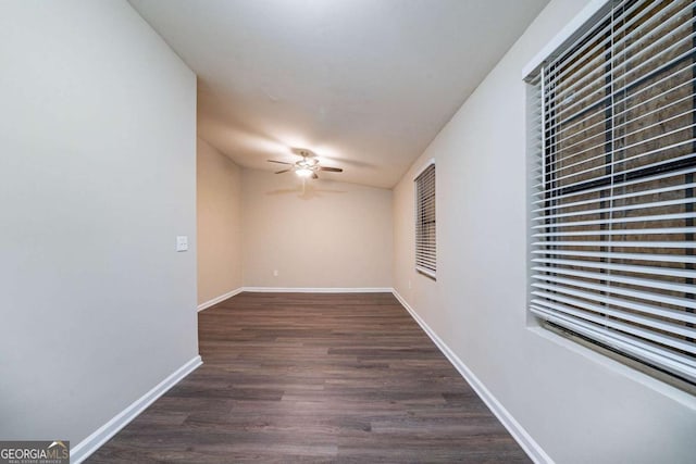 unfurnished room with ceiling fan, dark wood-type flooring, and baseboards