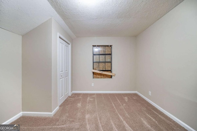 carpeted empty room with a textured ceiling and baseboards