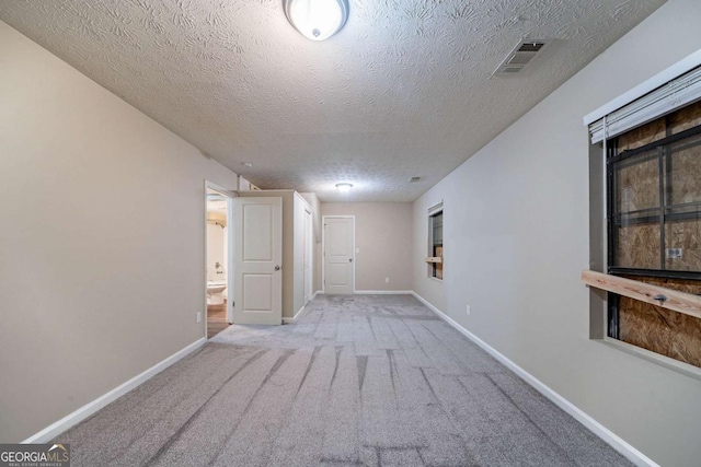 carpeted spare room with a textured ceiling and baseboards