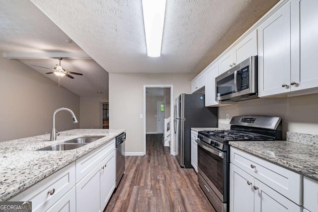 kitchen with appliances with stainless steel finishes, a sink, dark wood finished floors, white cabinets, and ceiling fan
