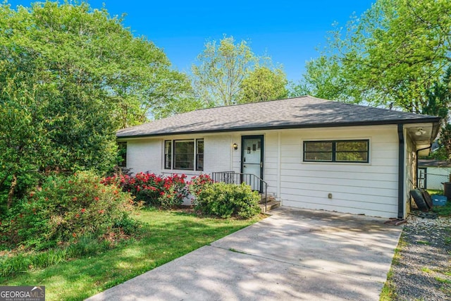 ranch-style house with roof with shingles and concrete driveway