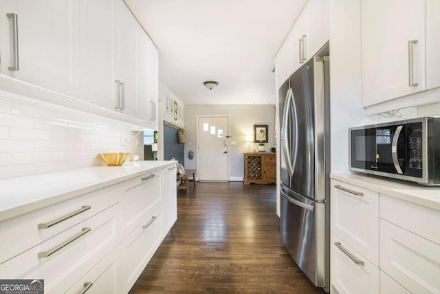 kitchen featuring appliances with stainless steel finishes, tasteful backsplash, dark wood-type flooring, and light countertops