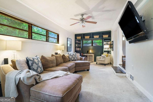 carpeted living area featuring a ceiling fan, crown molding, and baseboards