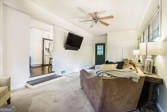 carpeted living area with a ceiling fan and baseboards