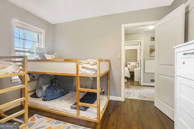 bedroom featuring wood finished floors, attic access, and baseboards