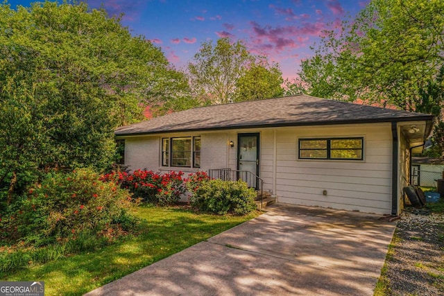 ranch-style home featuring a shingled roof and a front yard