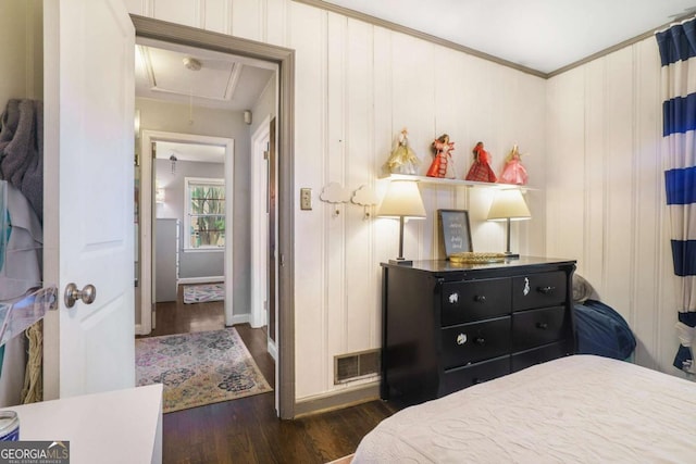 bedroom with attic access, wood finished floors, crown molding, and baseboards