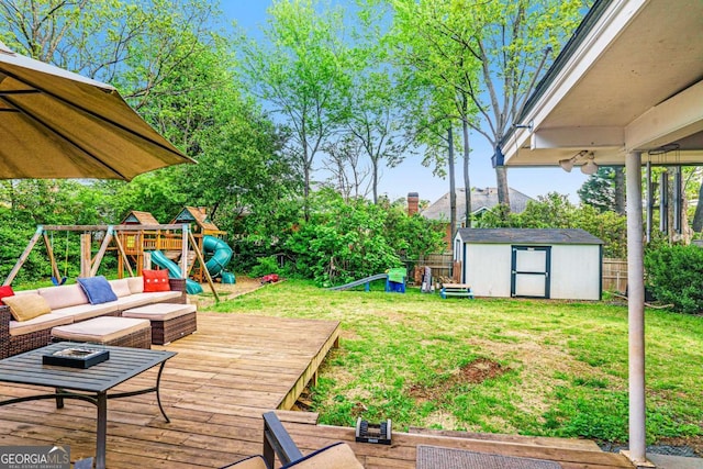 deck with a storage shed, a playground, and an outbuilding