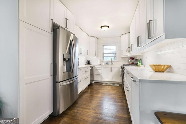 kitchen featuring appliances with stainless steel finishes, decorative backsplash, a sink, light countertops, and white cabinetry