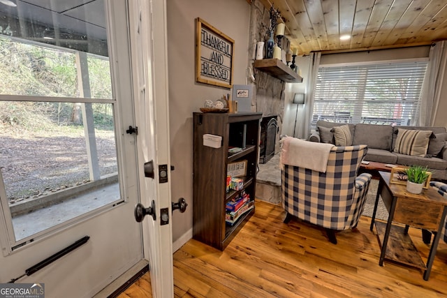 doorway featuring healthy amount of natural light, light wood-style flooring, and wooden ceiling