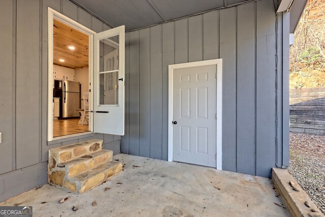 property entrance with board and batten siding and fence