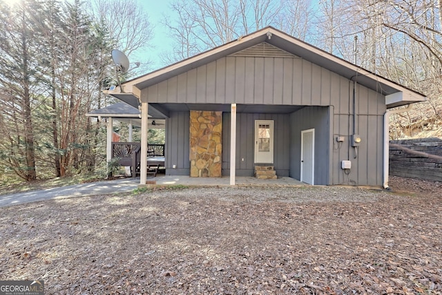 view of front facade featuring stone siding, fence, and covered porch