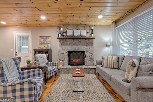 living area with light wood finished floors, recessed lighting, a stone fireplace, and wooden ceiling