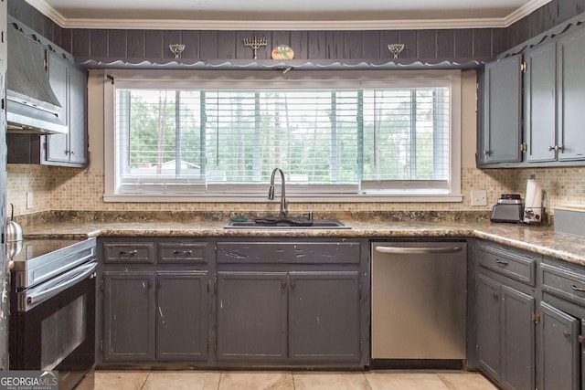 kitchen featuring appliances with stainless steel finishes, a sink, crown molding, healthy amount of natural light, and dark countertops