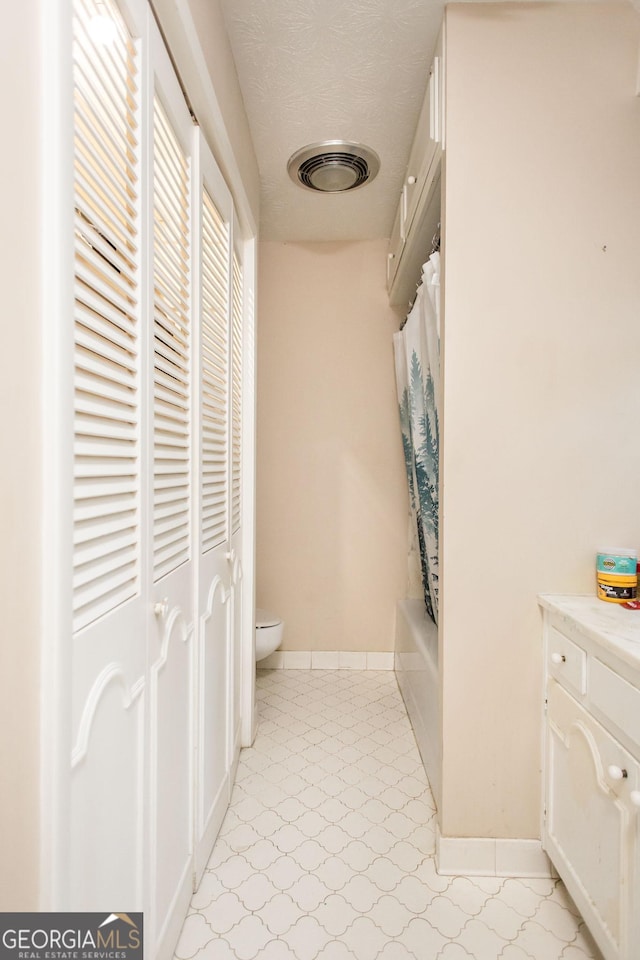 bathroom with tile patterned floors, toilet, baseboards, and shower / tub combo with curtain
