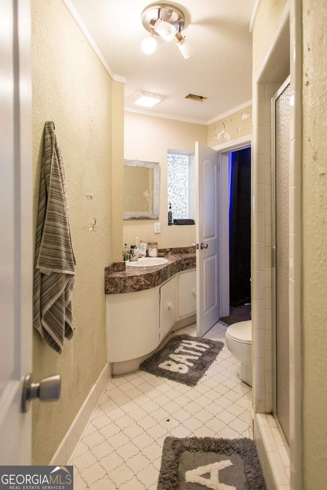 bathroom featuring ornamental molding, toilet, vanity, a stall shower, and a textured wall