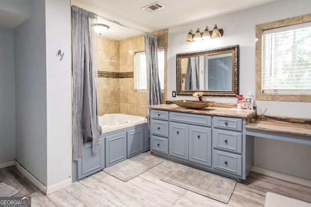 full bathroom featuring wood finished floors, vanity, shower / bathtub combination with curtain, and baseboards