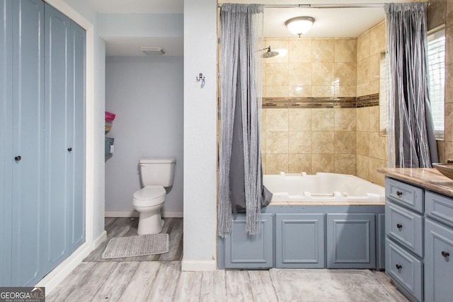 bathroom with toilet, wood finished floors, vanity, shower / bath combo, and baseboards