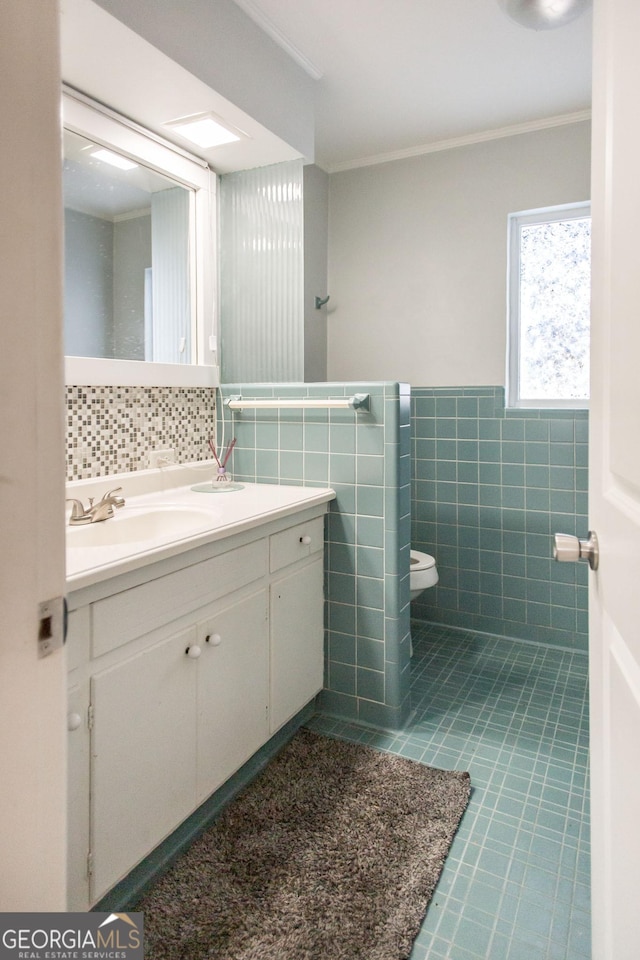 half bathroom featuring tile patterned floors, crown molding, toilet, tile walls, and vanity