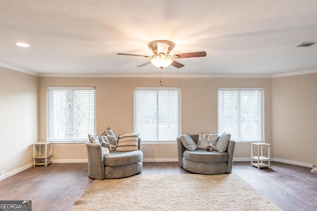 sitting room featuring wood finished floors, ceiling fan, crown molding, baseboards, and a textured ceiling