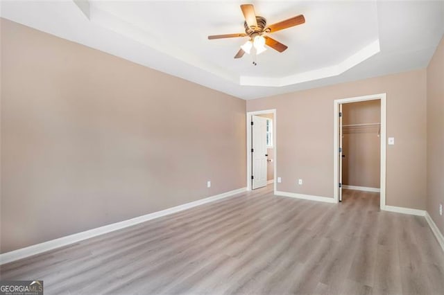 5805 Eagles Feather Ln, Riverdale, GA 30274 - unfurnished bedroom with a raised ceiling, light wood-style floors, baseboards, a spacious closet, and a closet