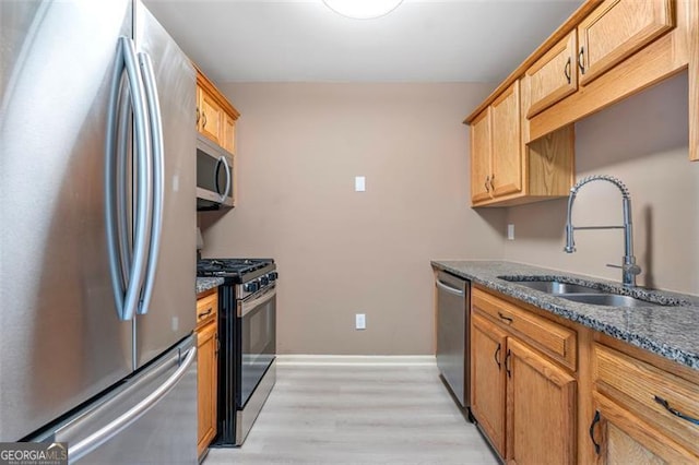 5805 Eagles Feather Ln, Riverdale, GA 30274 - kitchen with stainless steel appliances, a sink, light wood-style floors, dark stone countertops, and baseboards