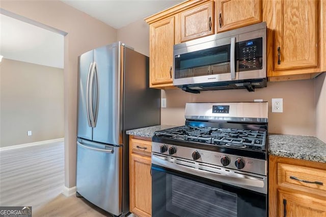 5805 Eagles Feather Ln, Riverdale, GA 30274 - kitchen with stainless steel appliances, light wood-style flooring, baseboards, and light stone countertops